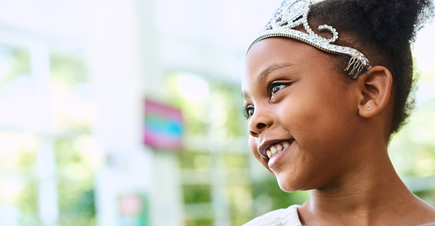 little girl smiling wearing crown in lobby of pediatric hospital