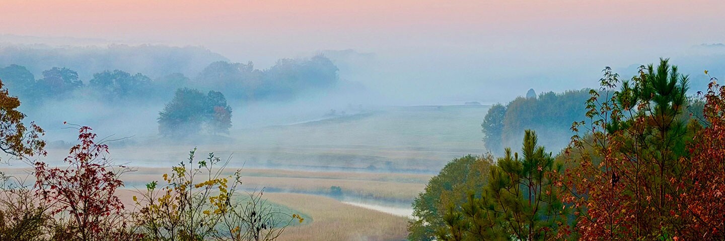 Misty valley with river and fall colors.