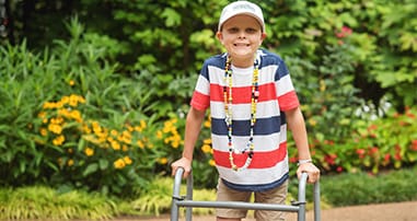 Cancer patient with walker smiling in garden wearing beads of courage
