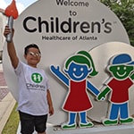 Children's patient smiling in front of sign