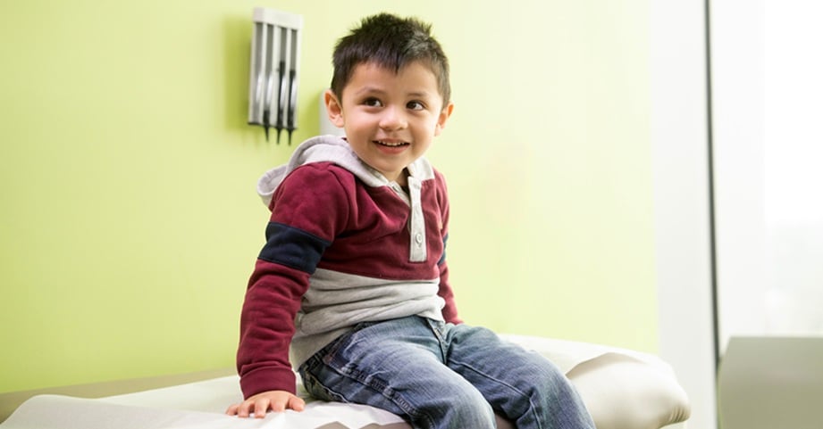 Young boy sitting on exam table in clinic