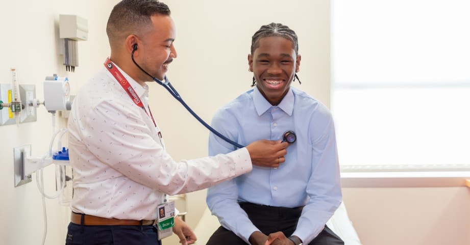 Male doctor checking heart of teenage boy in clinic
