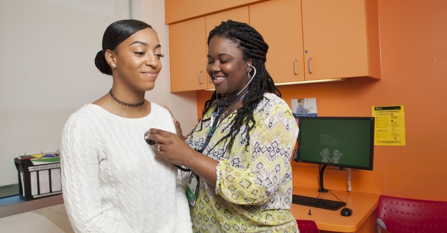 Female doctor checking heart of teenage girl in clinic