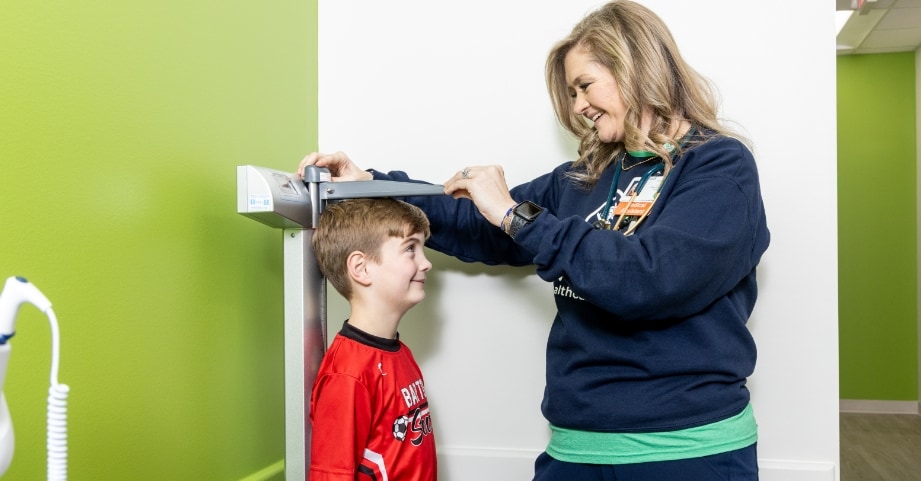 Medical assistant measuring height of elementary school aged boy