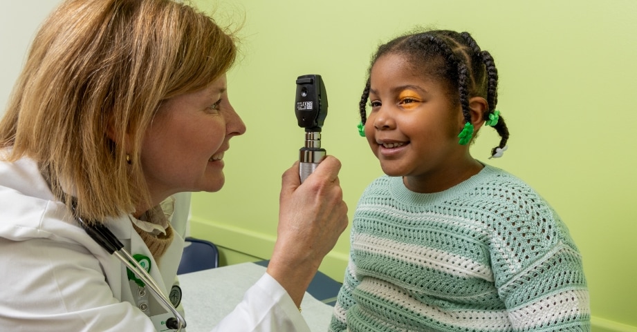 Advanced practice provider checking eyes of elementary school aged girl