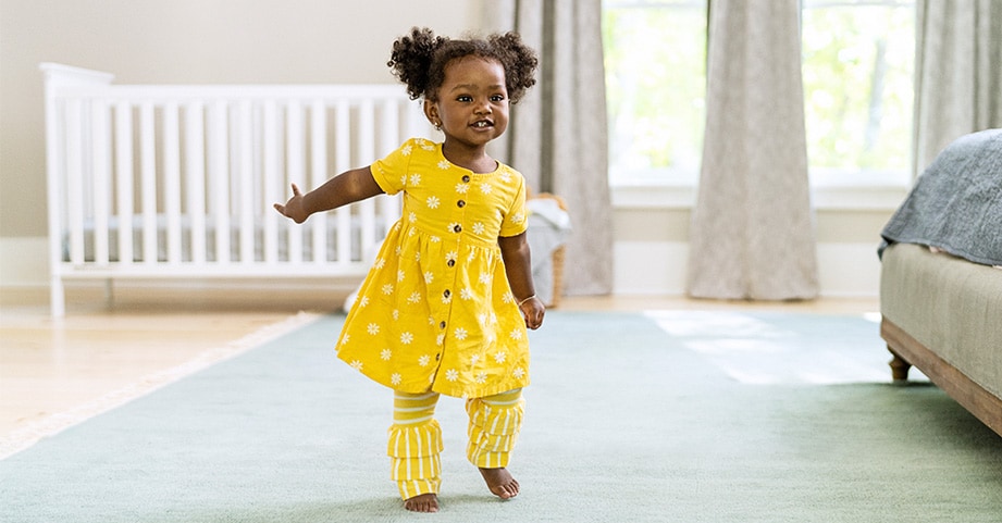 Baby girl in pigtails taking first steps