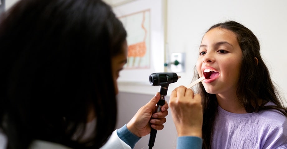 Female provider examining mouth of girl in clinic