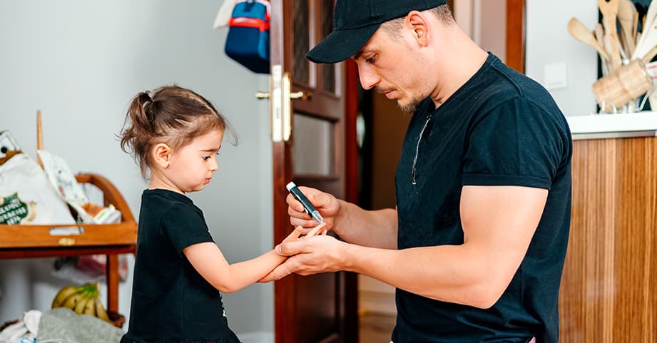 Dad checking child's blood sugar levels