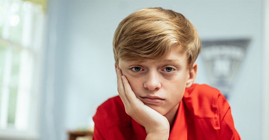 Teen boy sitting at desk looking sad and disinterested