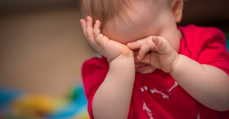 Baby girl rubbing her eyes with hands
