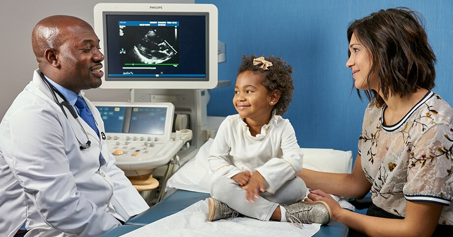 young girl with doctor and mom in clinic room