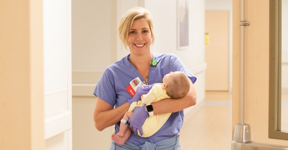 A cardiac catheterization nurse holds an infant in the Children’s Heart Center