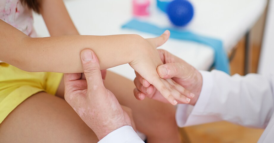 Doctor examining child's wrist for Juvenile Arthritis