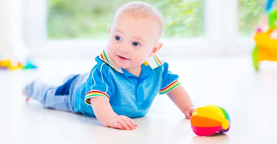 Baby on its stomach playing with a ball during tummy time 2