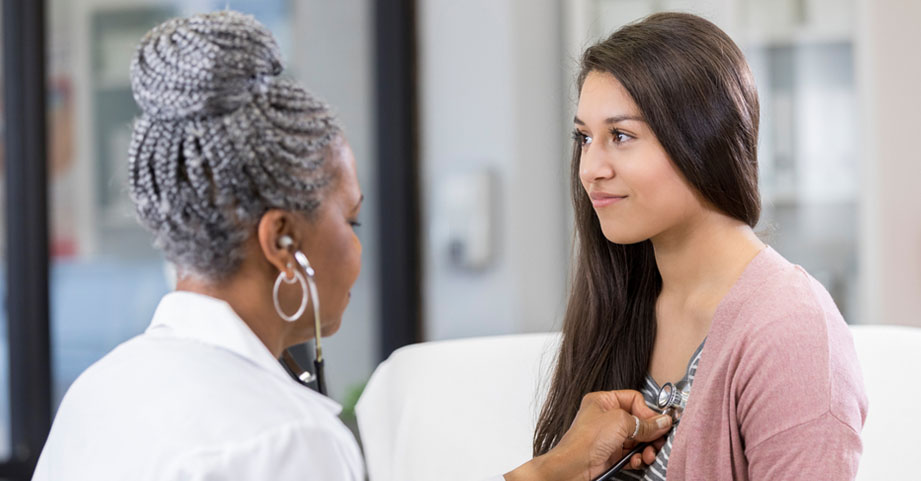 Pediatrician examining teen girl athlete