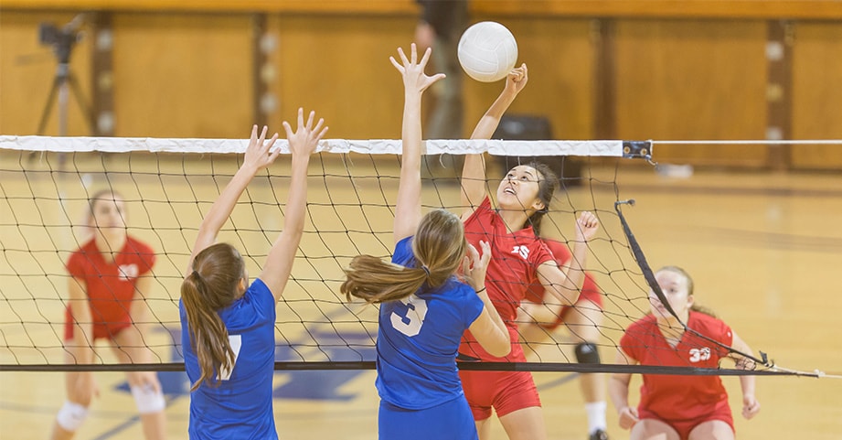 Teen spikes volleyball over net
