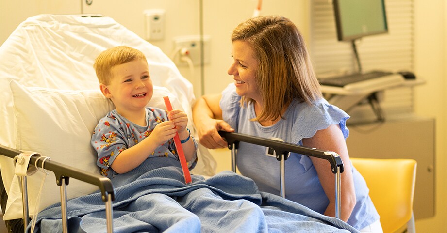 Parent sits with their child after surgery. 