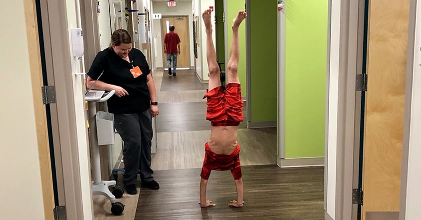 Boy recovering from pediatric orthopedic hip condition doing a handstand