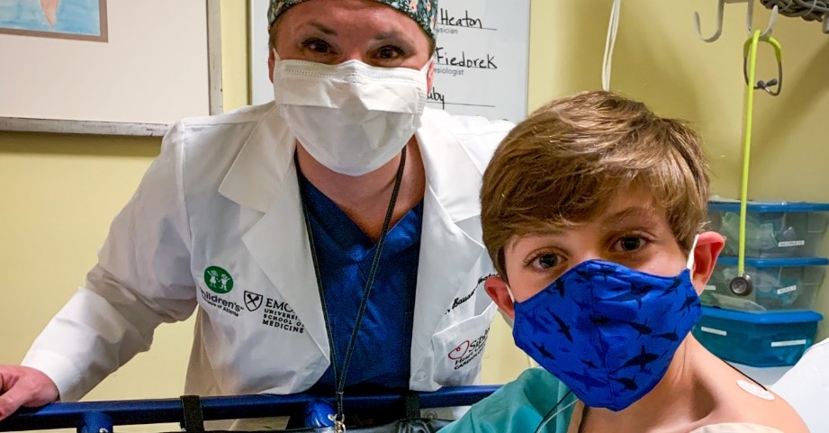 pediatric heart patient boy smiling in a mask before heart surgery with masked heart doctor
