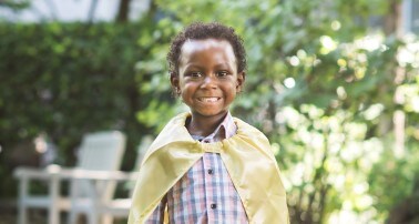 boy smiling wearing cape at pediatric hospital