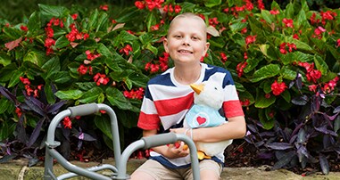 Child sitting with Aflac duck in garden