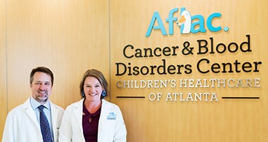 Physicians standing in front of Aflac sign
