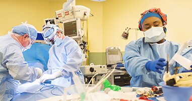 3 doctors performing procedure in pediatric operating room