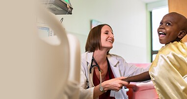 doctor laughing with pediatric patient in cape