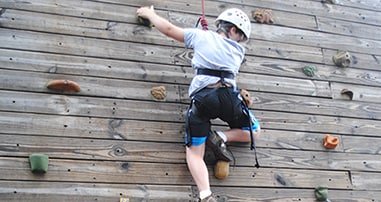 Camper climbing rock wall at pediatric summer Camp No Limbitations
