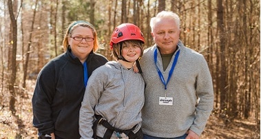 Child smiling with parents at camp