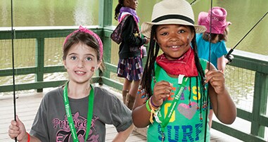 Girls smiling on fishing dock at Camp Braveheart