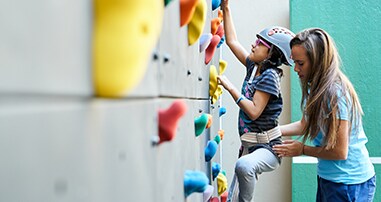 rehab therapist helping patient climb rock wall
