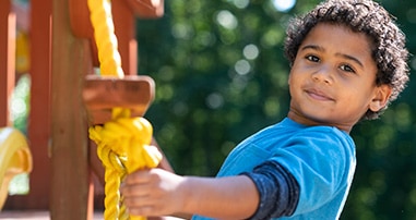Boy on playground holding yellow rope