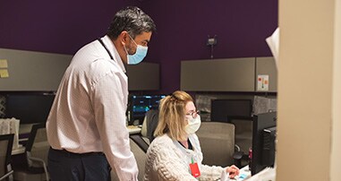 A doctor looks over a nurse’s shoulder at the nurse’s station in a pediatric hospital