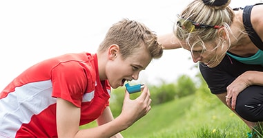 Pre teen athlete using inhaler for asthma attack