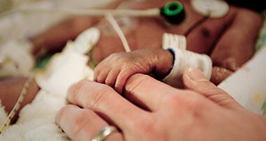 nicu baby holding pediatric nurse's hand