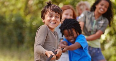 Kids play tug of war at camp.