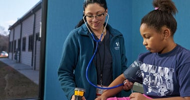 nurse taking girl's blood pressure