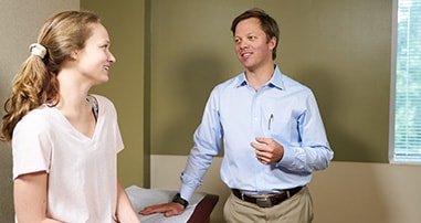 Dr. Willimon talks to young adult hip patient in clinic.