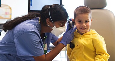 Dr. Shah examines a young boy's ear during a clinic visit.