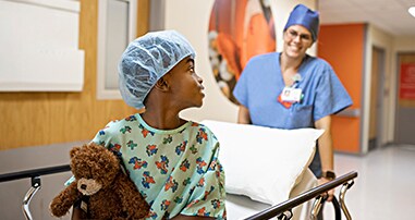 Young boy patient being taken into surgery with surgical nurse