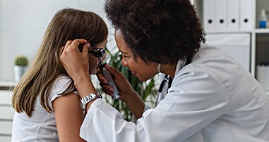 Young girl patient getting her ears looked at by a pediatric ENT doctor