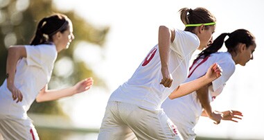 Teen soccer players performing running drills 