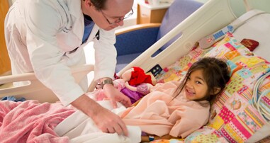 doctor checking on girl in hospital bed