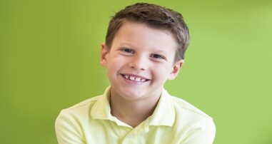 Child smiling with yellow shirt on