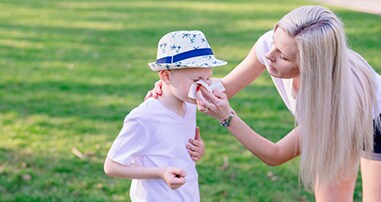 Mother helping child blow nose
