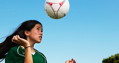 teen girl heading soccer ball