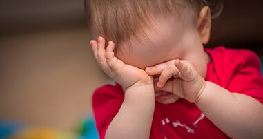Baby girl rubbing her eyes with hands