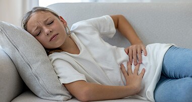 Girl with stomachache laying on the couch