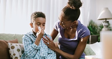 boy sneezing at home too sick for school